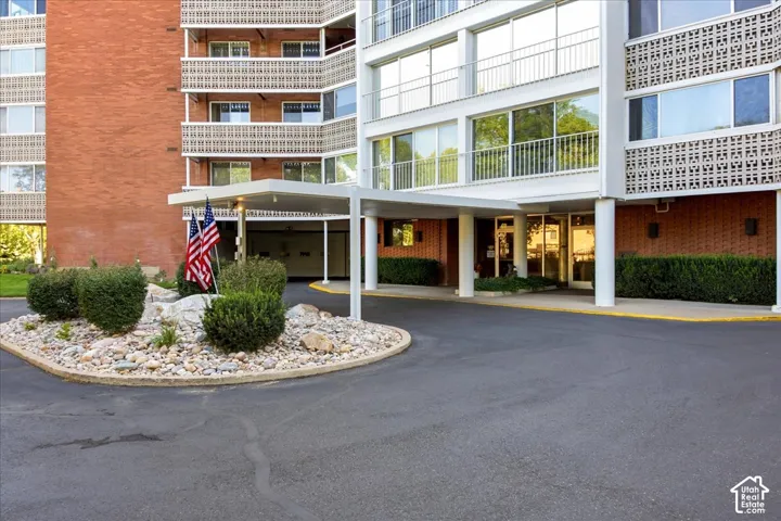 Building exterior with red brick and white-framed windows, a covered entrance, and a landscaped rock garden