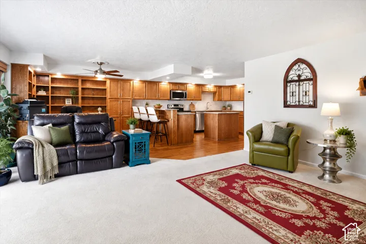 Open-concept living area featuring a kitchen with wood cabinetry, stainless steel appliances, and a breakfast bar