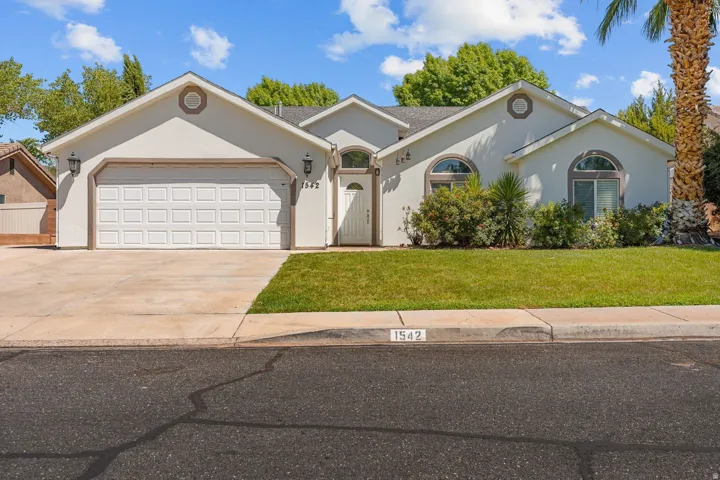Stucco exterior with arched windows, an attached two-car garage, and a concrete driveway