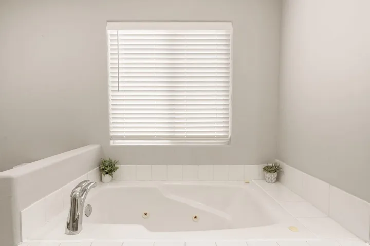 Soaking tub with white tile surround and integrated chrome fixtures