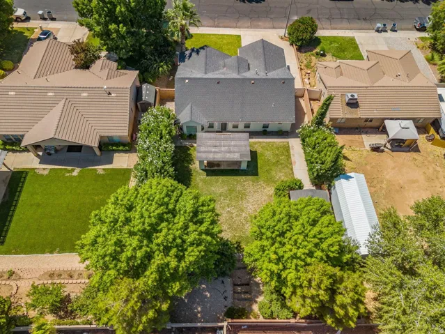 Expansive backyard featuring a shaded patio structure and mature trees