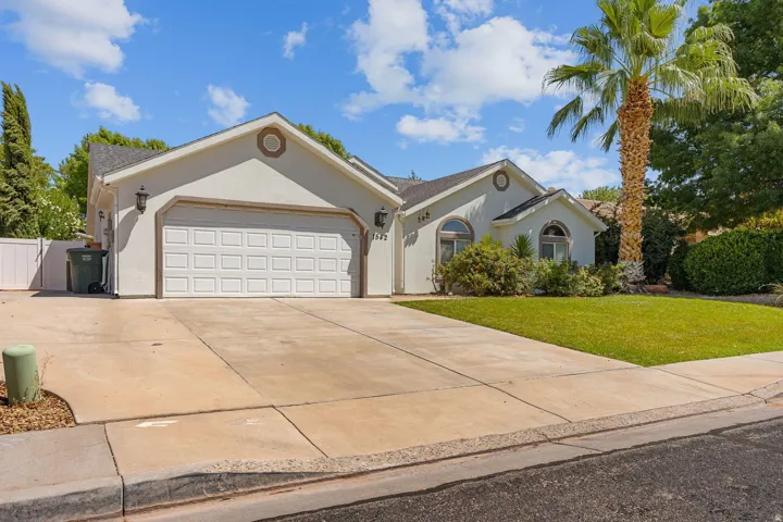 Stucco exterior with a two-car garage, concrete driveway, and front lawn