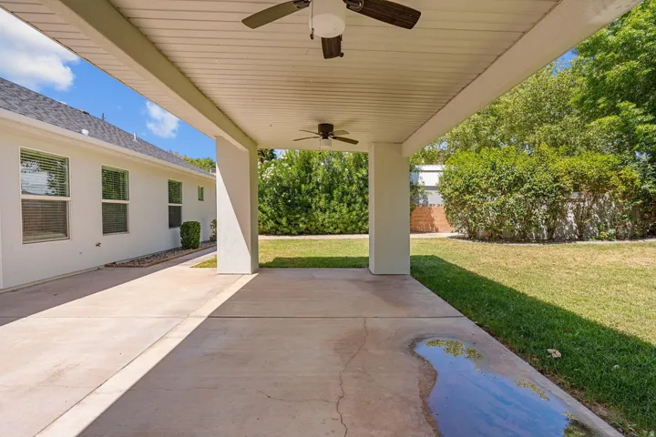Covered patio featuring concrete flooring, ceiling fans, and structural columns