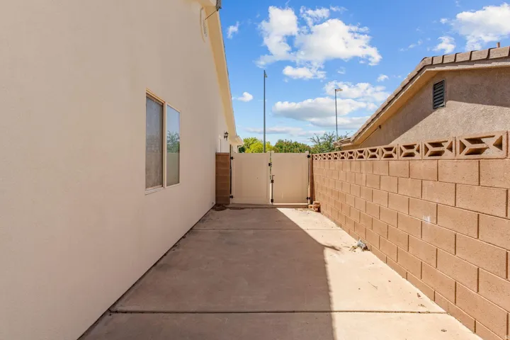 Concrete walkway with a block wall featuring decorative top blocks and a privacy gate