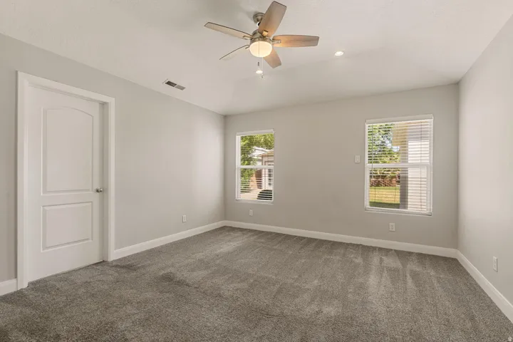 Spacious room featuring vaulted ceiling, recessed lighting, ceiling fan, neutral wall tones, and plush carpeting