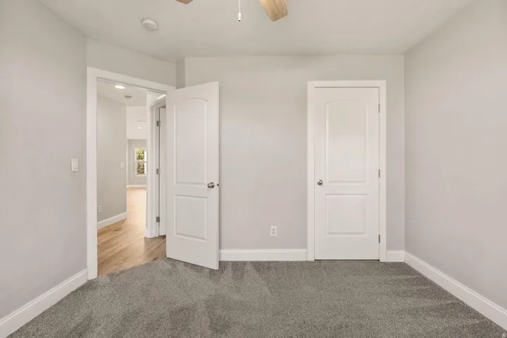 Neutral-toned walls, ceiling fan, and grey carpet flooring