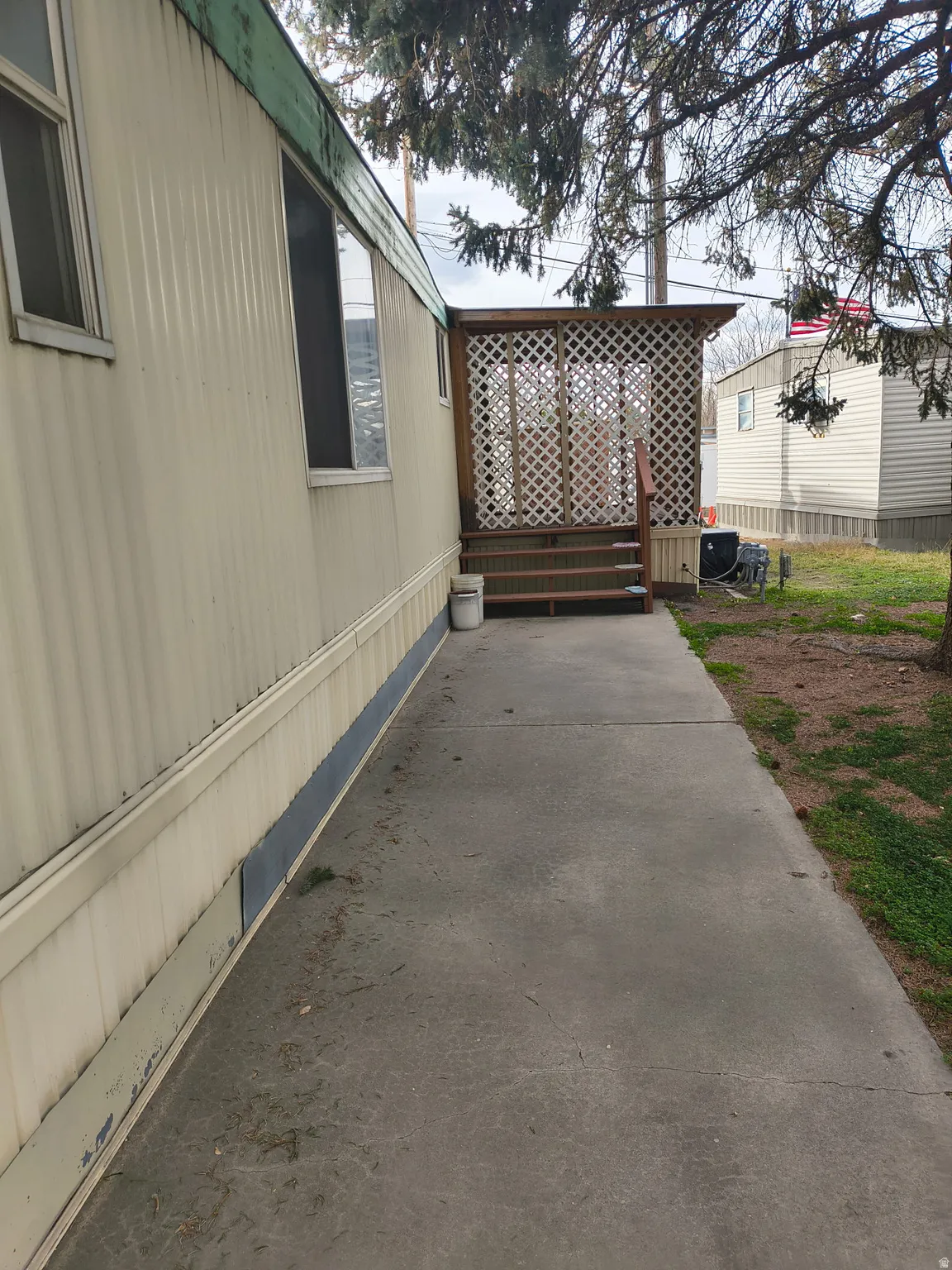 Wood deck with lattice screen, covered entryway, and concrete walkway