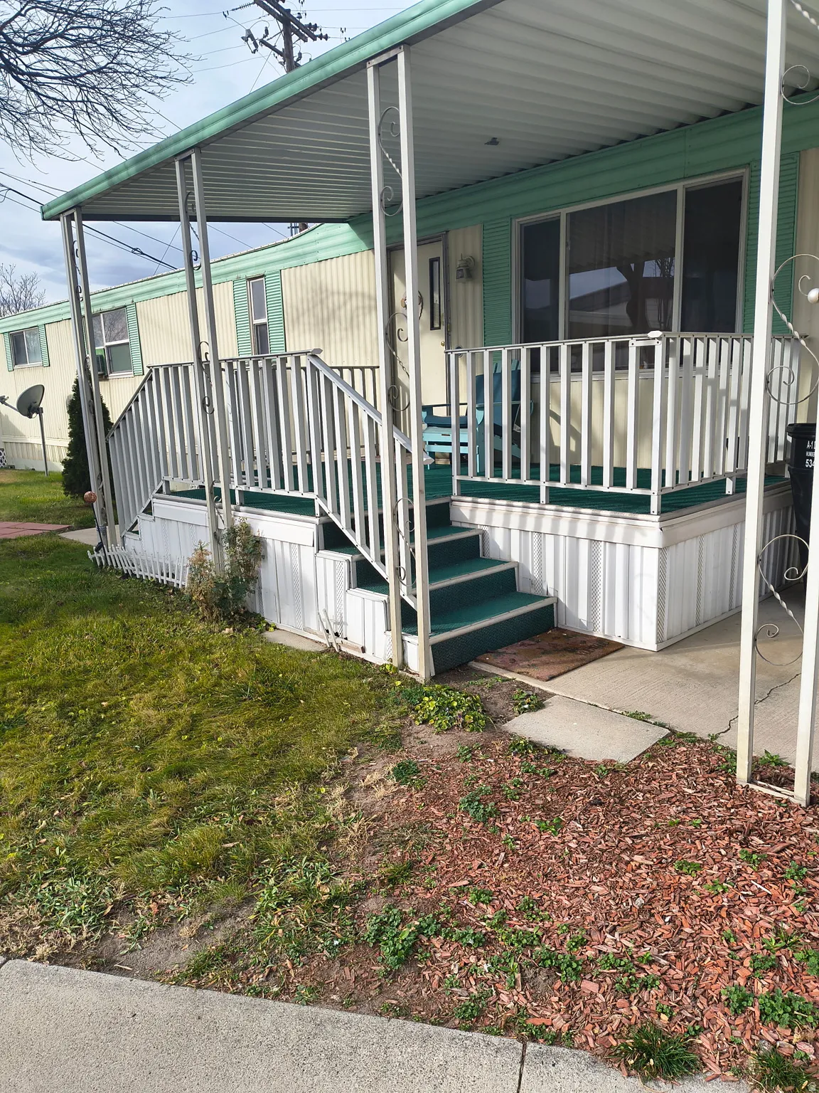 Covered porch with white metal railings and green-carpeted steps