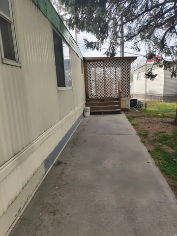 Wood deck with lattice screen, covered entryway, and concrete walkway