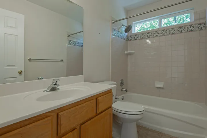 Bathroom with a light wood-finish vanity, integrated sink, and chrome faucet