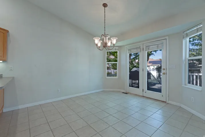 Tiled flooring, vaulted ceiling, double-pane windows, and a chandelier with glass shades