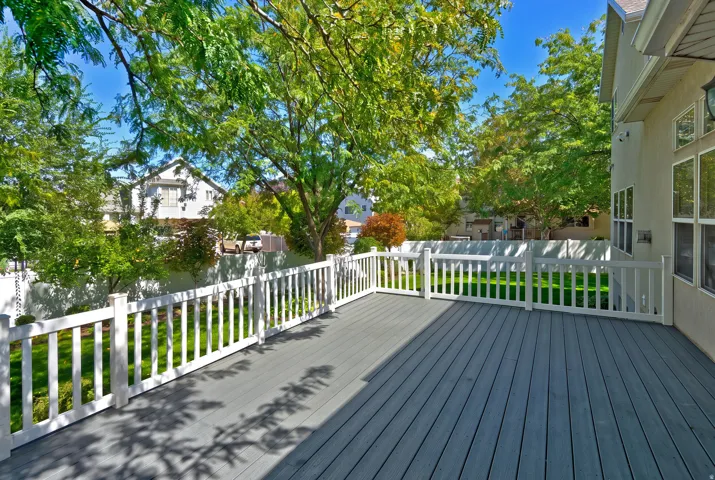 Expansive outdoor deck featuring composite decking, white picket railings, and a manicured lawn beyond
