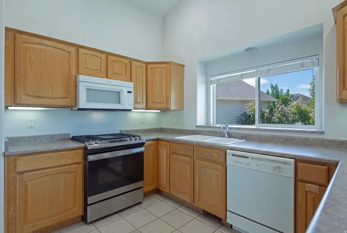 Kitchen featuring oak cabinetry, light-toned countertops, a stainless steel range, and an integrated dishwasher