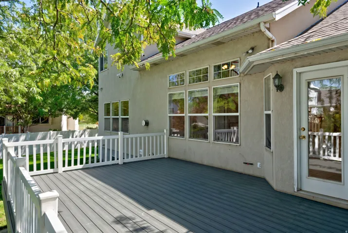 Outdoor deck with gray composite decking, white railing, and stucco exterior