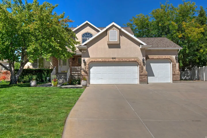 Stucco exterior with brick accents, arched windows, an attached two-car garage, and a concrete driveway
