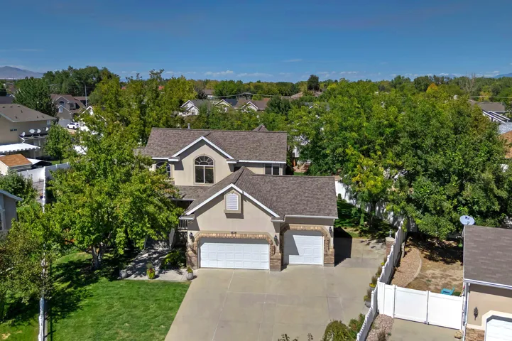 Stucco exterior with stone accents, attached two-car garage, mature landscaping, and a fenced side yard