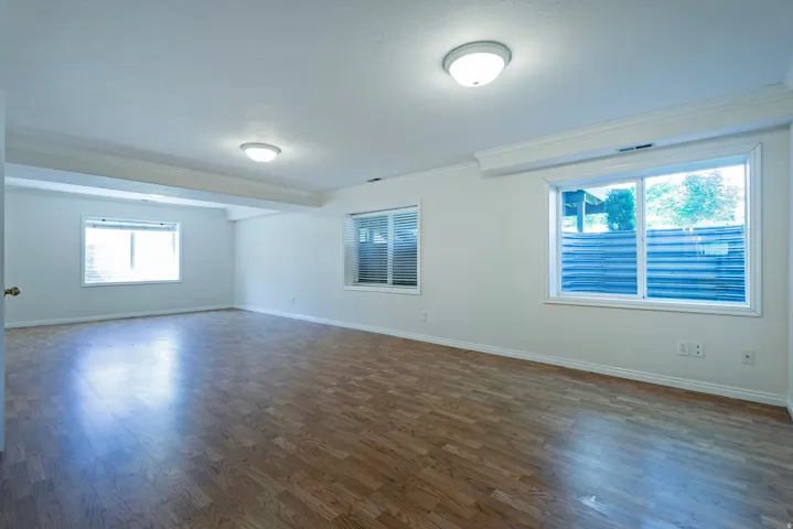 Wood-finish flooring, multiple windows, crown molding, and recessed lighting fixtures