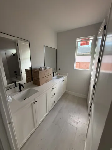 Dual vanity with white cabinetry and integrated sinks, matte black faucets, and rectangular mirrors