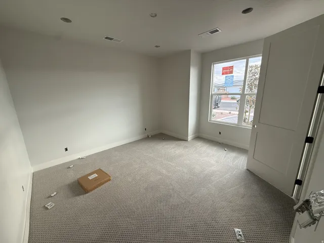 Recessed ceiling lighting, neutral carpeting, white wall finishes, and a multi-pane window