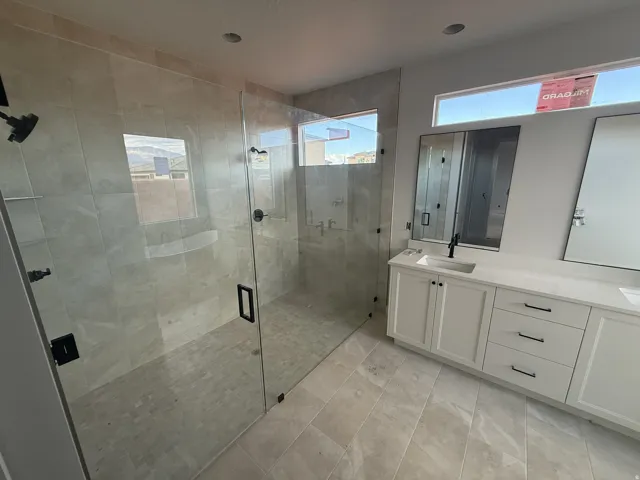 Glass-enclosed shower with matte black fixtures, integrated shelving, and large format tile