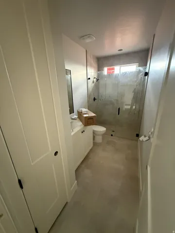 Full vanity with integrated sink, glass-enclosed shower, transom window, and tile flooring