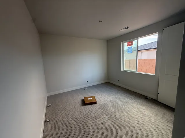 Carpeted room with a recessed ceiling light, a window, and a white paneled door