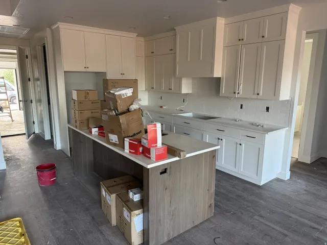 White shaker cabinetry, wood-finish flooring, white solid surface countertops, a white subway tile backsplash, and a central island with wood-finish paneling