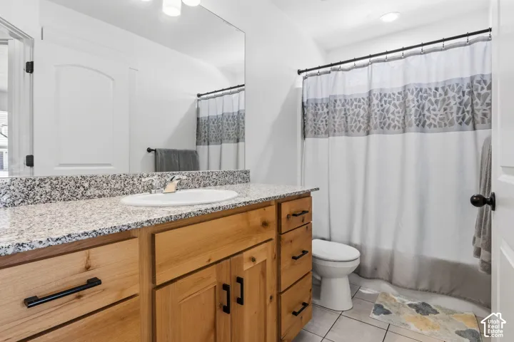 Single vanity with a granite countertop, undermount sink, and wood-finish cabinetry