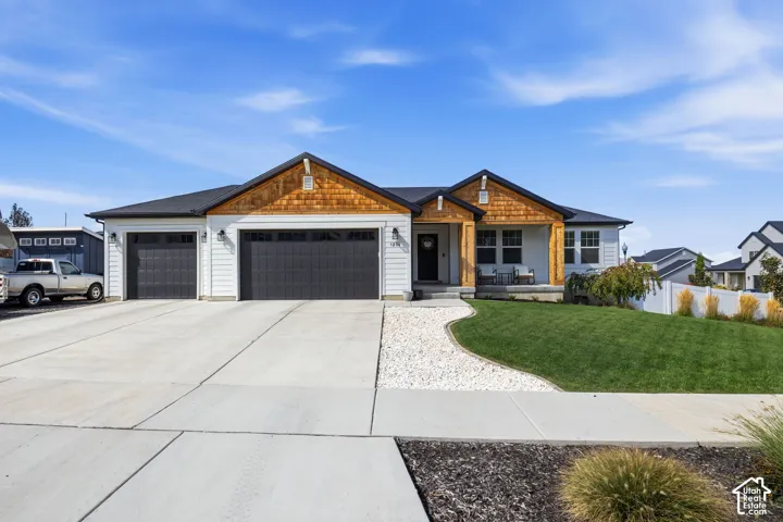 Single-story residence featuring white siding, dark garage doors, and natural wood shake accents