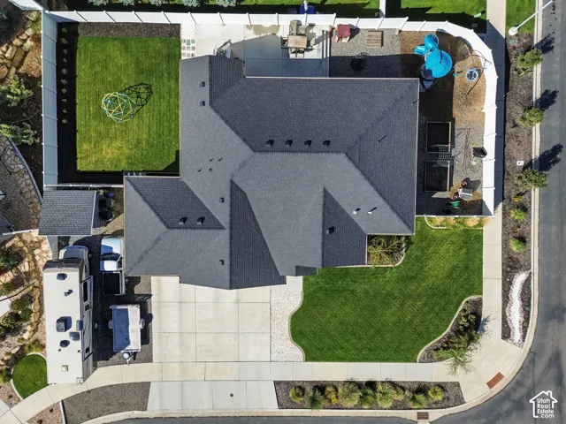 Expansive paved driveway and pathway, manicured front lawn, private fenced backyard with grass area, and a dark shingle roof