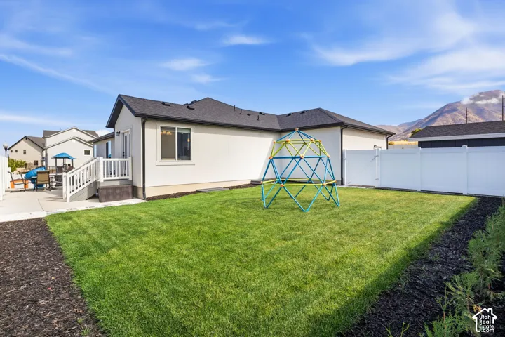 Expansive backyard featuring a well-maintained lawn, privacy fencing, and a concrete patio with steps leading to the residence
