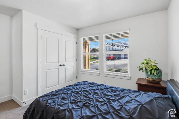 Double-door closet with arch paneling, dual windows with blinds, and neutral wall tones