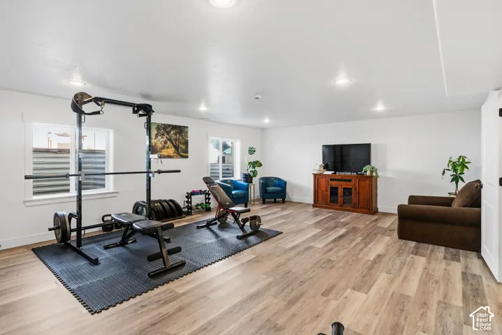 Spacious room featuring wood-finish flooring, white walls, multiple recessed lights, and two windows