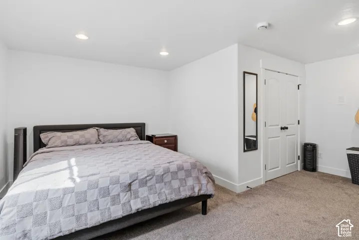 White walls, recessed lighting, white interior door, and grey carpet