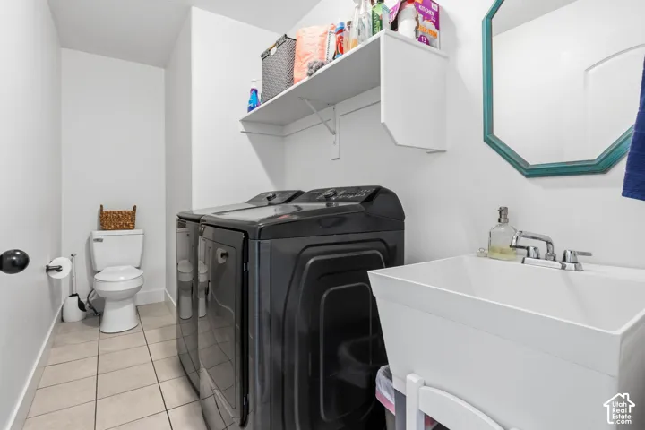 White walls with a floating shelf, a utility sink with a chrome faucet, and tile flooring