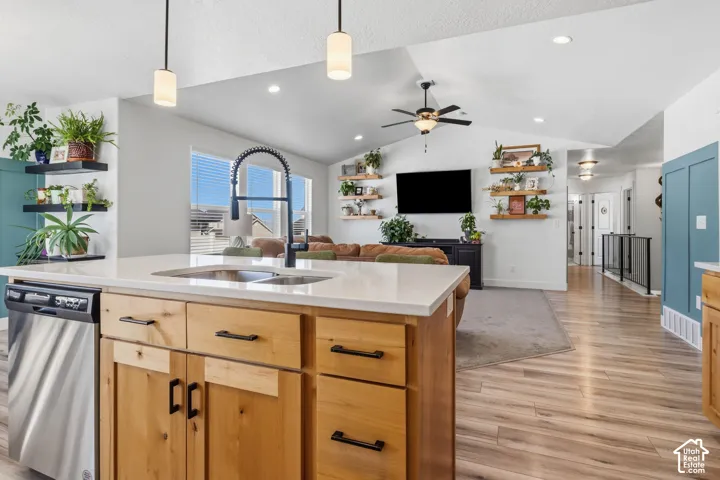 Kitchen island with light wood-finish cabinetry, integrated stainless steel dishwasher, and a black gooseneck faucet