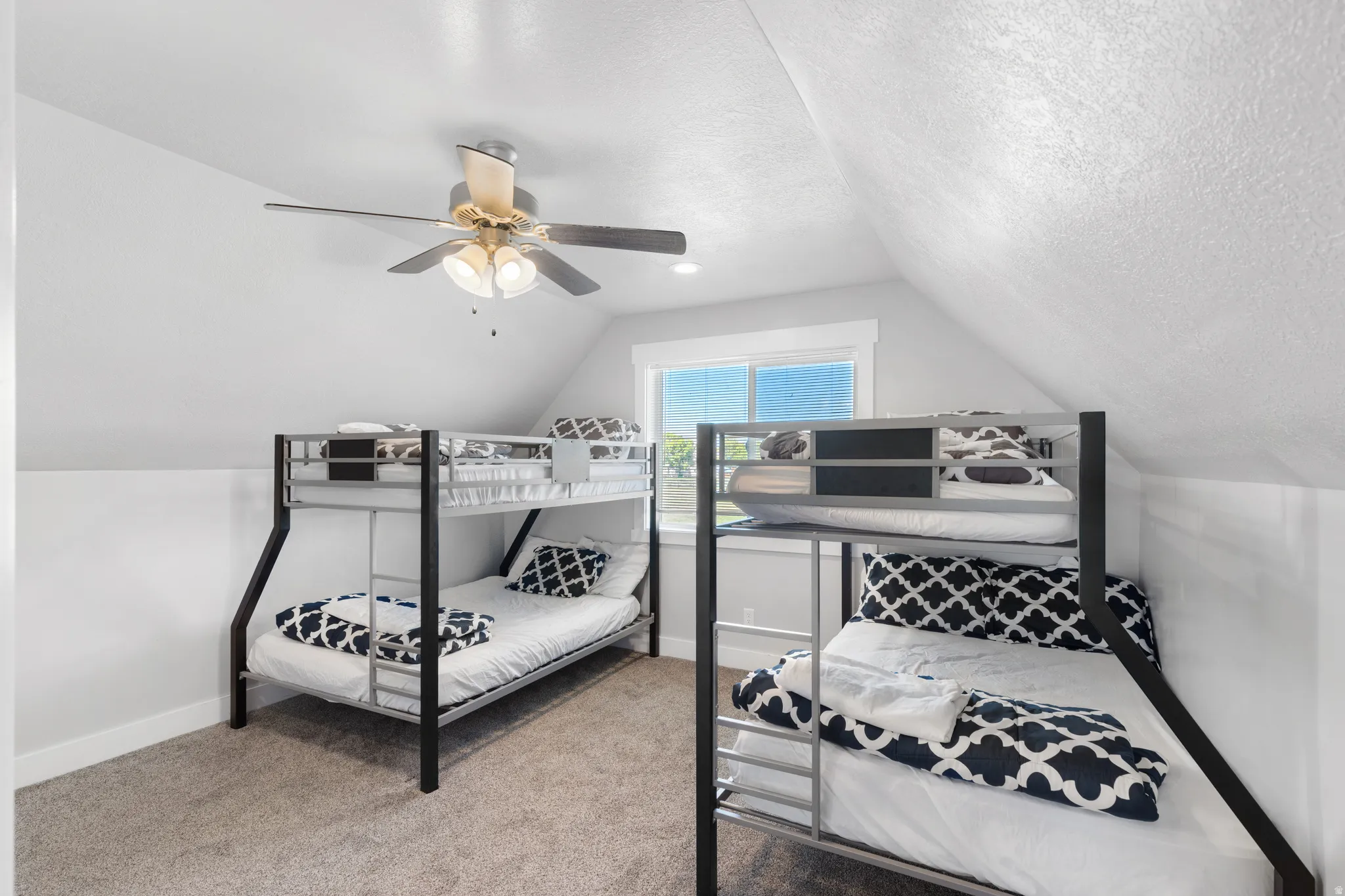 Carpeted room with a pitched ceiling and a ceiling fan