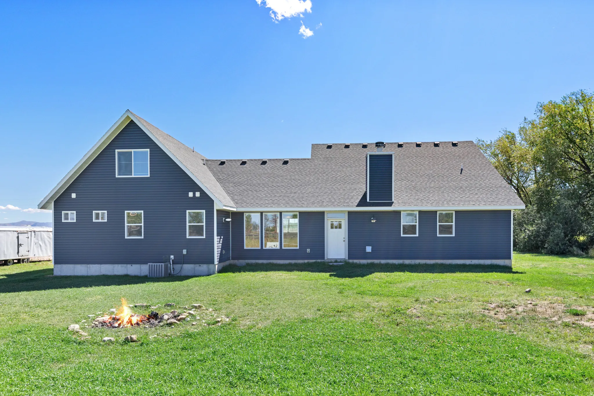 Expansive green lawn with a stone-lined fire pit