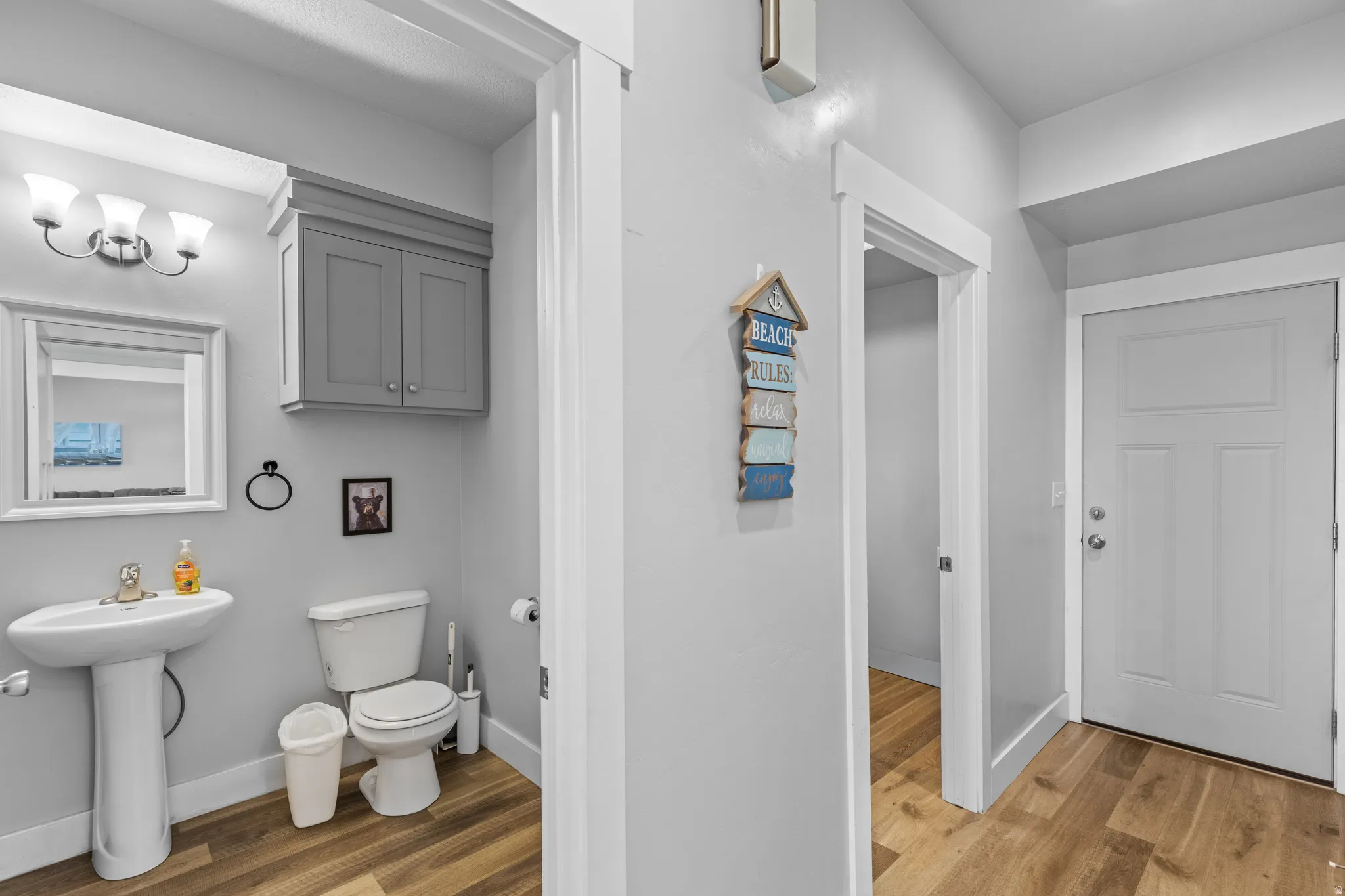 Bathroom featuring a pedestal sink, wall-mounted vanity cabinet, and wood-finish flooring