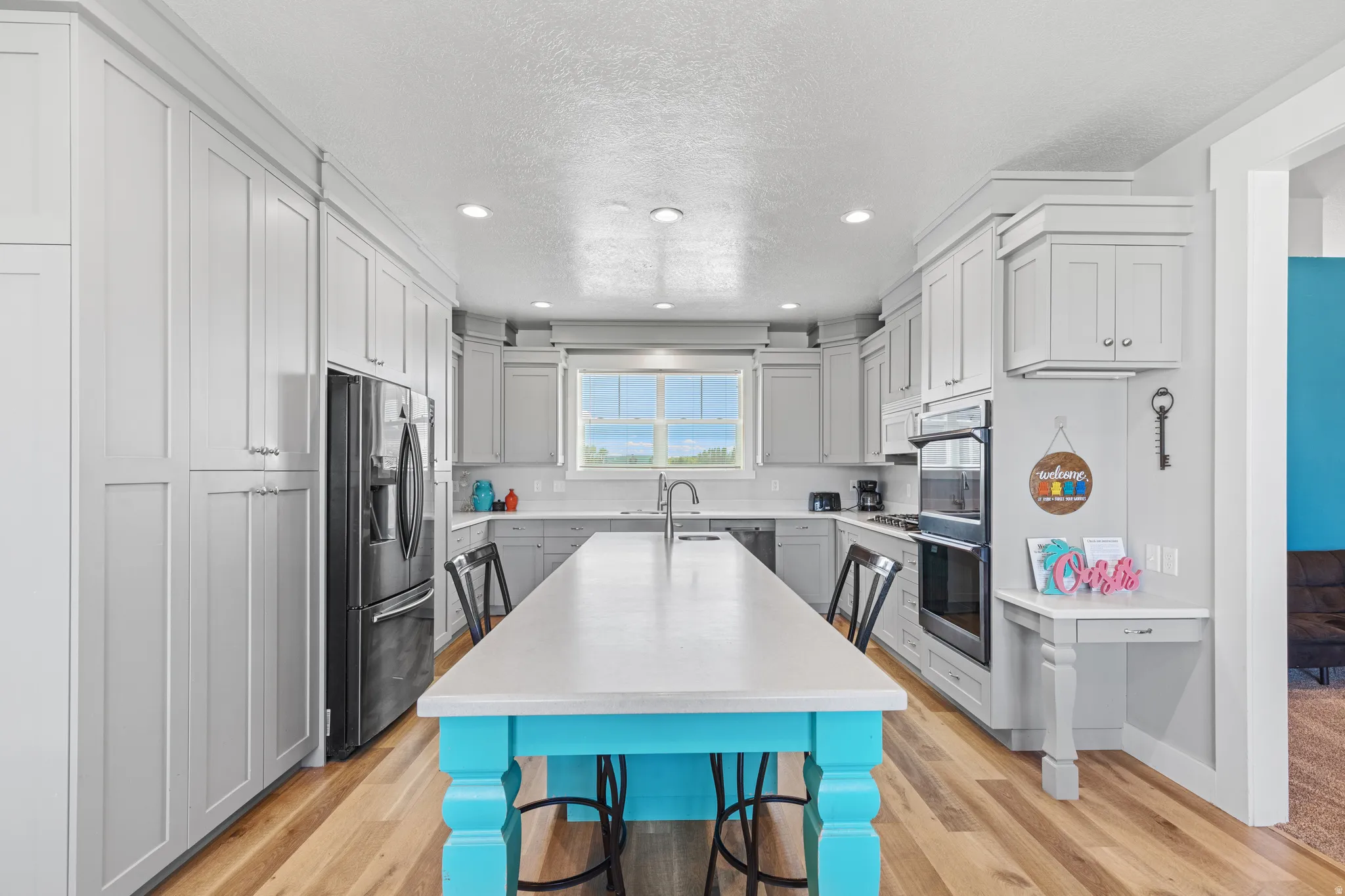 Spacious kitchen featuring extensive cabinetry, wood-finish flooring, recessed lighting, double wall oven, and a large central island with seating