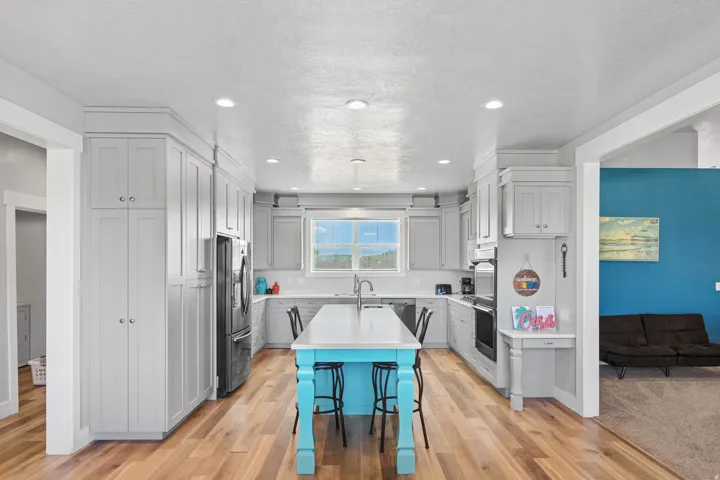 Contemporary kitchen featuring light wood-finish flooring, light-toned cabinetry, stainless steel appliances, and an island with a contrasting base