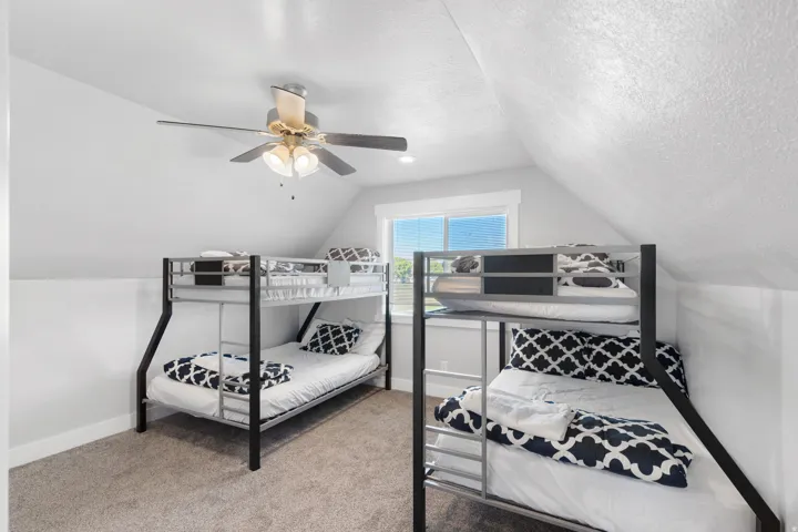 Carpeted room with a pitched ceiling and a ceiling fan