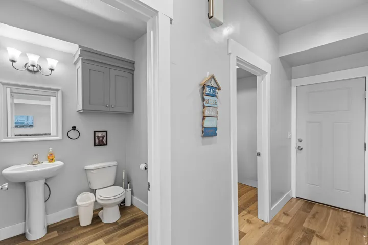 Bathroom featuring a pedestal sink, wall-mounted vanity cabinet, and wood-finish flooring