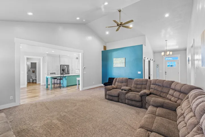 Vaulted ceilings with a ceiling fan, recessed lighting, and wood-finish flooring
