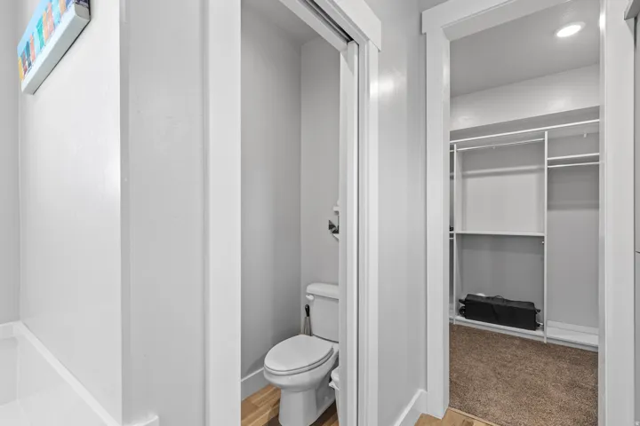 Built-in closet shelving, toilet, and wood-finish flooring