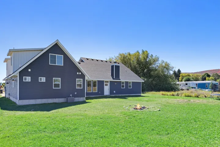 Expansive green lawn with a two-story structure featuring dark siding and white trim