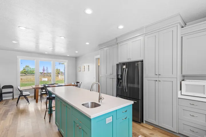 Kitchen featuring a turquoise island with a white countertop, stainless steel sink, wood-finish flooring, and recessed lighting