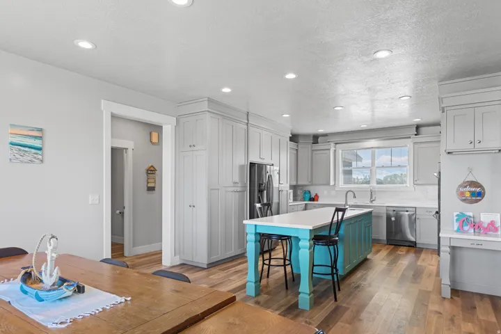 Spacious kitchen featuring an oversized island with seating, stainless steel appliances, abundant cabinetry, and wood-finish flooring