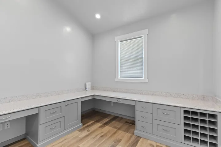 Built-in gray cabinetry with ample storage, integrated desk space, light-toned countertops, and wood-finish flooring