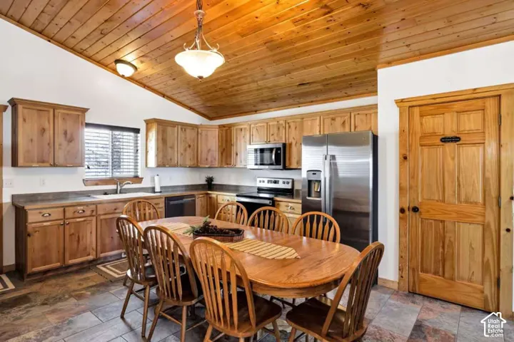 Vaulted wood-finish ceiling, wood-finish cabinetry, stainless steel appliances, and slate-style flooring